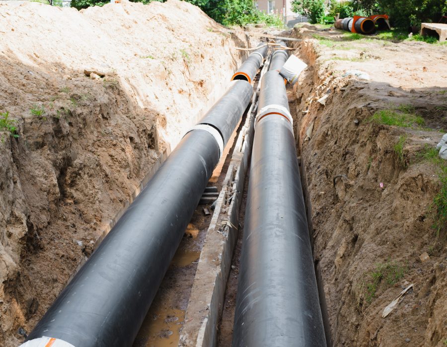 Plumbing repair. Installation of new industrial street water pipes in dug hole in two lines, outdoors.