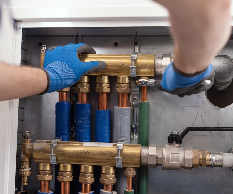 Professional plumber installing plumbing manifolds at home, home improvement and repair concept
